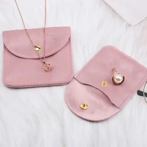 Pink velvet jewelry pouches with gold metal snaps on white faux fur background