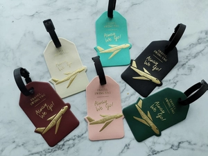 Flat lay of colorful faux leather luggage tags with gold foil airplane and travel motifs