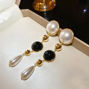 Elegant 18k gold plated drop earrings with white pearls and black beads on a jewelry box