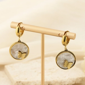 Detail view of golden butterfly relief on circular shell textured drop earrings