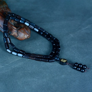 Macro shot of dark sandalwood beads with engraved character and a wooden tassel