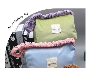 Detail of corduroy handbags in green, blue, and brown with pleated handles and labels