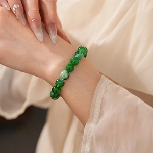 Detailed view of green round bead bracelet on wrist with smooth polished finish