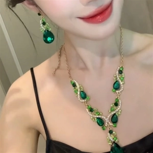 Close-up of model wearing green teardrop zircon necklace and matching gold earrings set