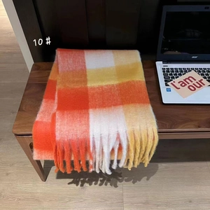 Close-up of a warm orange and white rainbow plaid scarf with long soft fringes