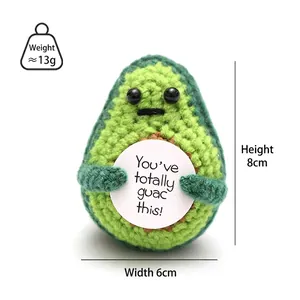 Macro shot of handmade crochet avocado doll with a positive message card and soft texture
