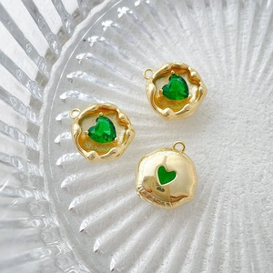 Detailed macro of 14k gold plated heart pendants with green zircon in a glass tray