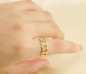 Close-up of a 18k gold-plated stainless steel Cuban link chain ring worn on a finger
