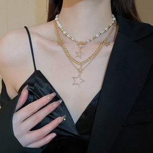 Detail of layered gold star pendant necklace with pearls on a professional fashion model