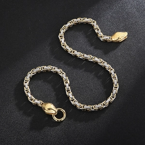 Détail de la chaîne tressée bicolore avec deux têtes de serpent sculptées en gros plan