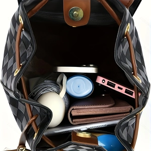 Top view of spacious interior of plaid backpack with brown drawstring and daily essentials