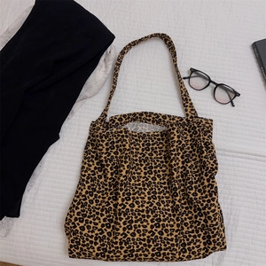 Dettaglio della borsa tote in tela leopardata con occhiali neri e libri sparsi
