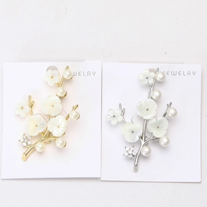 Détail de broches fleur de prunier en or et argent avec pétales blancs et perles d'eau douce