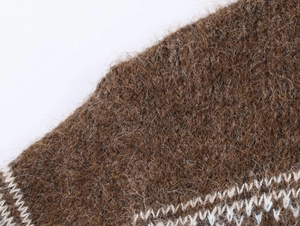 Macro shot of dark brown knit fabric with white geometric jacquard pattern and fuzzy texture