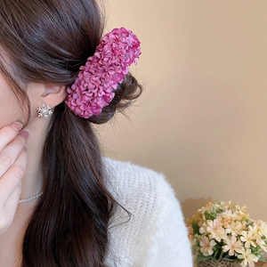 Detail of elegant rose purple fabric flower hairpin accessory shown in a model side view