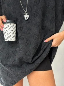 Détail d'un sweat à capuche noir oversize avec motif cœur en relief et collier chaîne cœur