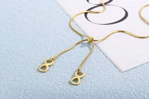Macro detail of golden snake chain necklace with infinity pendants and adjustable sliding clasp