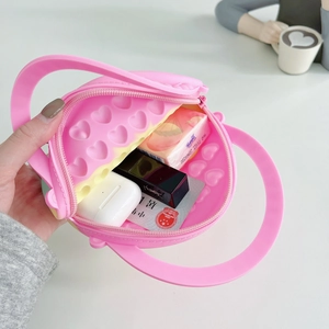 Close-up of pink silicone heart pop-it bag showing internal storage for small items