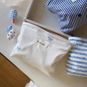 Detail of blue and white striped and checkered cosmetic bags with bow embroidery