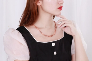 Collana a catena a torsione oro rosa e anello minimalista indossati da una modella