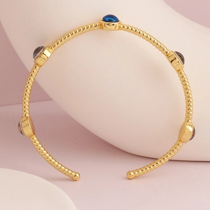Close-up of gold-plated twisted rope bracelet with blue and grey inlaid gemstones
