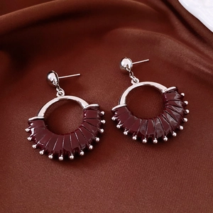 Detailed macro of vintage silver earrings with deep red lacquer and beaded texture
