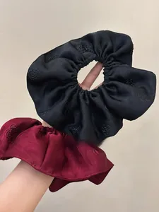 Detail of elegant satin scrunchies with 3D rose pattern in black and burgundy red