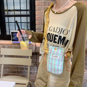 Close-up of minimalist checkered canvas crossbody bag and olive green patchwork t-shirt