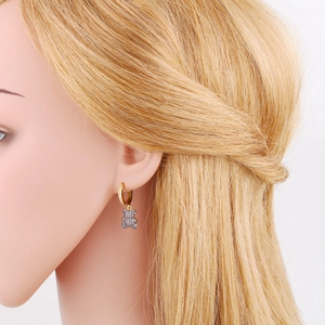 Close-up of gold hoop earrings featuring a micro-paved zircon teddy bear pendant