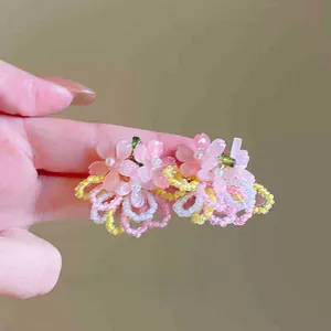 Detailed view of hand-woven floral hair clip with pink petals and white bead core