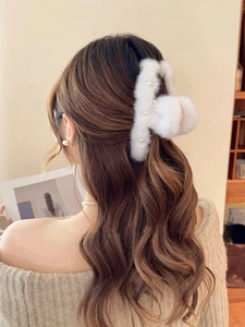 Rear view of a model wearing a plush white faux fur hair claw clip with pearl accents