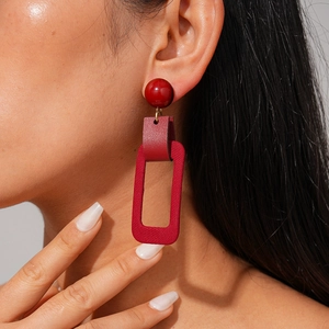 Red geometric resin and leather drop earrings shown on a model for scale and style