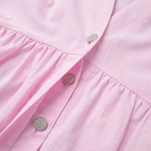 Detailaufnahme von rosa Leinenstoff-Set mit geprägten Silberknöpfen und Falten-Design