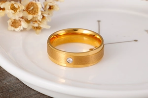 Dettaglio di un anello in titanio dorato con finitura spazzolata e singolo diamante incastonato