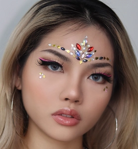 Macro shot of colorful teardrop and round rhinestones on a woman's forehead