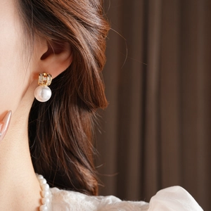Detail of elegant gold-plated pearl earring with diamond accent on model ear