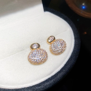 Close-up of gold-plated oval stud earrings with pavé-set shimmering cubic zirconia stones