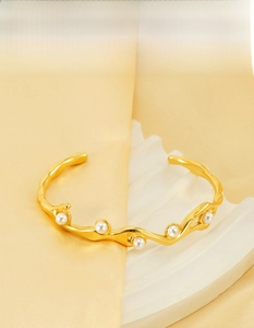 Dettaglio di un bracciale a onde in oro 18k con perle bianche su seta morbida