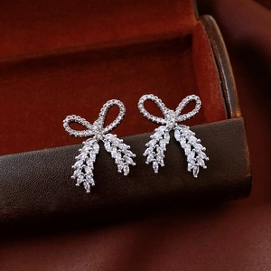 Close-up of silver bow earrings with marquise-cut zircon tassels on a jewelry box
