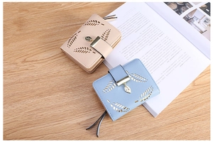 Detail of short leather wallets for women with leaf cutout and metal leaf pendant