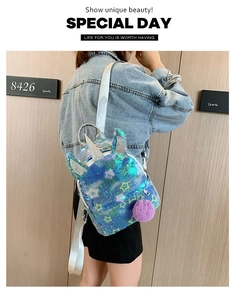 Girl wearing rainbow sequin unicorn backpack with star patterns and purple fur pom-pom charm