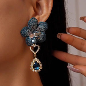 Détail de la boucle d'oreille fleur brodée avec des pierres bleues et des diamants