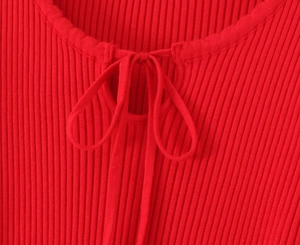 Close-up of red ribbed knit neckline featuring a delicate bow tie detail and texture