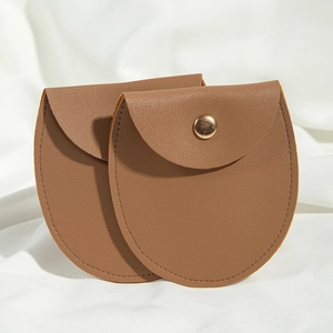 Close-up of brown PU leather jewelry pouches with snap button on white fabric