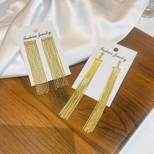 Macro detail of elegant long gold tassel earrings with zircon inlay on display card
