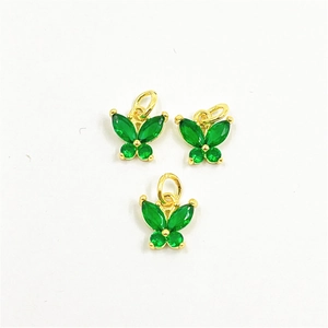 Détail macro de trois pendentifs papillon en laiton doré sertis de zircons verts brillants