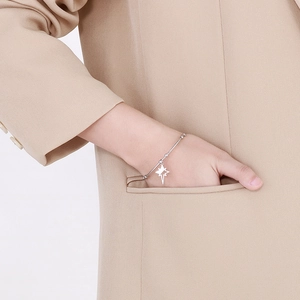 Close-up of silver star pendant bangle on wrist with a beige blazer background