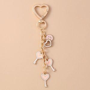 Detailed view of pink heart and key charms on a golden metal keychain for backpacks