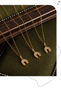Trois colliers avec pendentif fer à cheval doré et zircons sur fond vert texturé chic