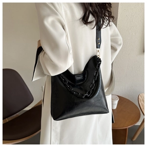Detail view of a black hobo shoulder bag with glossy oil-wax finish and chic chunky chain